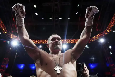 Boxer Oleksandr Usyk raises his arms in victory, his gloves high. He's a seasoned pro, not one of those top heavy amateurs.