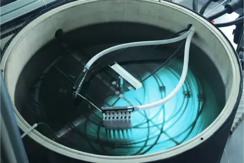Ein großer Tank mit Wasser, Rohren und einem Gerät zur Eisbildung. Hier wird ein **Eisspeicher selber bauen**-Projekt umgesetzt.