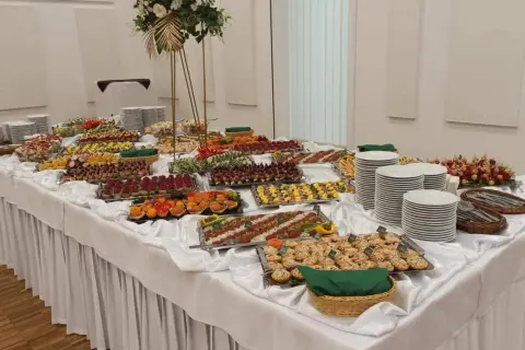 Stół z bogatym cateringiem: przekąski, sałatki, przystawki, talerze i dekoracje.