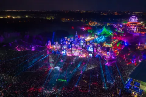 Nocny festiwal Tomorrowland 2026 w pełni. Tłumy ludzi, kolorowe światła, sceny w kształcie zamków i latające balony tworzą magiczną atmosferę.
