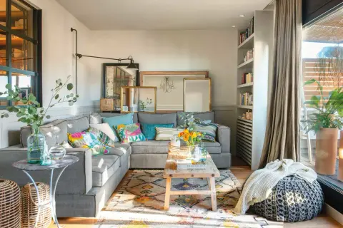 Acogedor salón con sofá gris, cojines coloridos y alfombra étnica. Un espacio que demuestra que las sencillas salas pequeñas pueden ser muy estilosas.