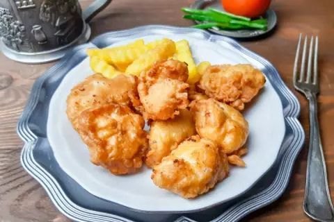 Chrupiące kawałki piersi z kurczaka w cieście naleśnikowym, podane z frytkami. Idealna przekąska!