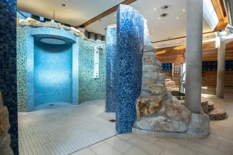 Moderne Duschen mit Mosaikfliesen und Felsenelementen in der Therme Regensburg laden zum Entspannen ein.