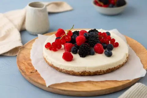 Kalter Hund: Ein cremiger Käsekuchen mit Beeren-Topping, serviert auf einem Holzbrett.