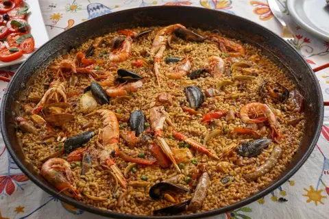 Une paella valenciana généreuse, débordant de riz, crevettes, moules et langoustines, prête à être dégustée.