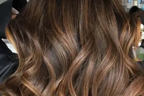 Glänzendes, glattes Haar mit Balayage in Braun-Caramel-Tönen, das wie flüssiges Gold fällt.