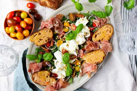 En härlig buffé med appertiff mat: mozzarella, tomater, prosciutto, ruccola och rostat bröd. Perfekt för en somrig förrätt.