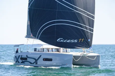Catamarano Excess 11 con vela nera che naviga in mare aperto.