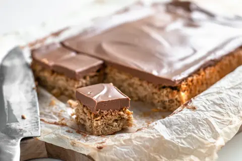 En bit av en långpanne kaka med nougat. Kakan har en krispig botten och toppas med ett lager choklad.
