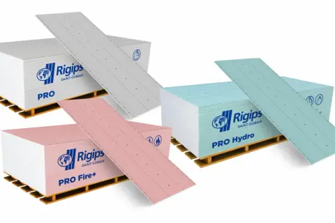 Różne rodzaje płyt gk: PRO (szara), PRO Fire+ (różowa) i PRO Hydro (niebieska), na paletach.