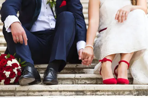 Brautpaar hält Händchen, rote Rosen & Schuhe. Perfekt für Ideen kleine standesamtliche hochzeit.