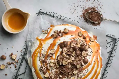 Ein köstlicher Banoffee-Kuchen, dekoriert mit Karamell, Schokostückchen und ganzen Schokokugeln. Perfekt für dein nächstes Banoffee Rezept!