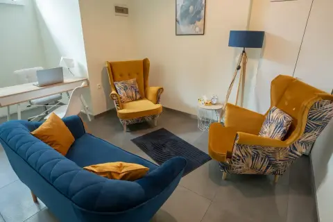 Wnętrze gabinetu psychologicznego z kanapą, fotelami i biurkiem.