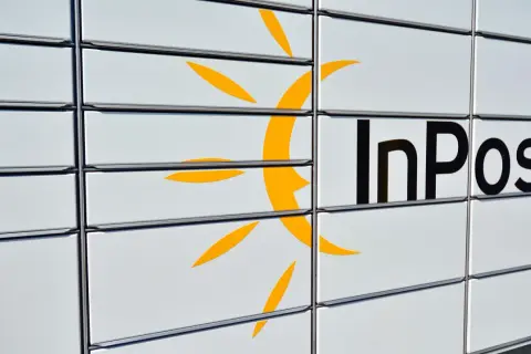 Zbliżenie na białą paczkomat InPost z żółtym logo i czarnym napisem.