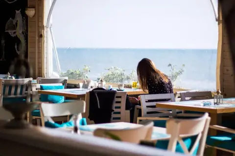 Kobieta siedzi przy stoliku w restauracji z widokiem na morze. Idealne miejsce, gdzie zjeść we Władysławowie.