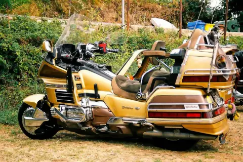 Złoty motocykl turystyczny z dużym bagażnikiem i wygodnymi siedzeniami.