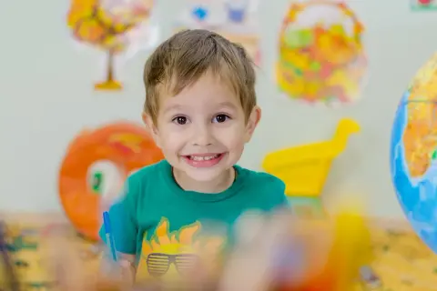 Niño sonriente con camiseta verde, aprendiendo sobre el mundo. Fomenta la autoestima en niños de 6 a 12 años.