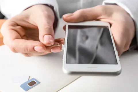 Maintenant, découvrez comment ouvrir le tiroir carte sim sans outil. Une main insère un trombone dans le téléphone.