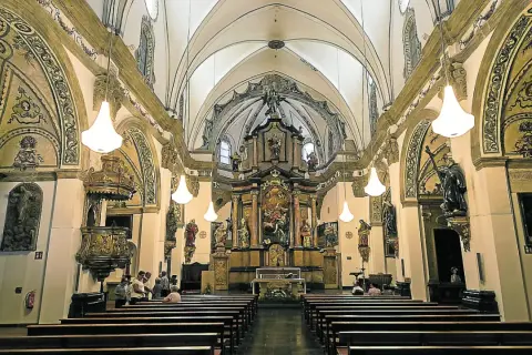 Interior de la iglesia de la Magdalena en Zaragoza, con bancos de madera, un retablo dorado y esculturas.