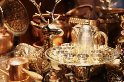 Glänzende bronzene Teekanne mit Tassen und Hirschfigur, perfekt für eine bronzene Hochzeit.