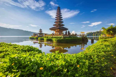 Świątynia Pura Ulun Danu Bratan na Bali podczas pory suchej. Woda spokojna, odbija wielopoziomową wieżę.