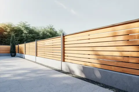 Ett modernt staket med horisontella ribbor i trä och grå betongsockel. En ensam cypress i kruka står vid staketet.