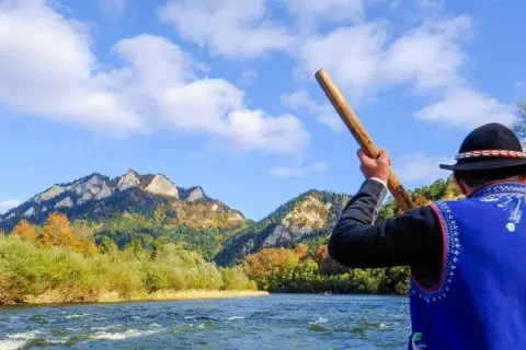 Flisacy Dunajec w tradycyjnych strojach płyną tratwą przez malowniczy przełom rzeki. Góry Pieniny jesienią zachwycają kolorami.