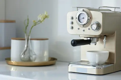 Kaffee-Ecke-Ideen: Eine elegante Espressomaschine mit Tasse und einer kleinen Vase mit Blumen.