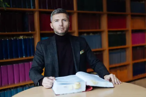 Mężczyzna w garniturze z książkami, przygotowuje się do obrony w sądzie bez adwokata.