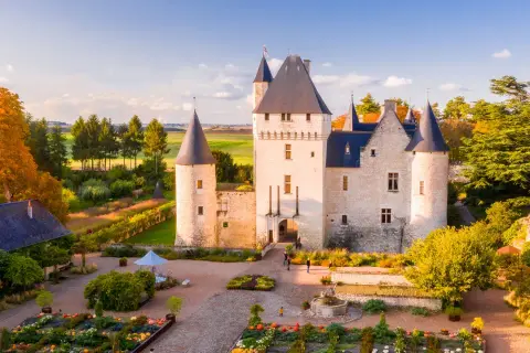Le château du Rivau, propriété de la famille, s'illumine sous le soleil d'automne, entouré de jardins colorés.