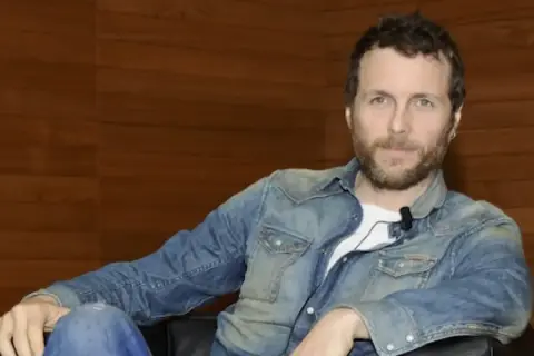 Jovanotti, con la sua camicia di jeans, sembra pronto a cantare "Mi fido di te".