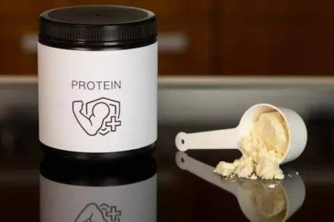 Barattolo di proteine in polvere e misurino con polvere. Le proteine sono fondamentali per la costruzione muscolare.