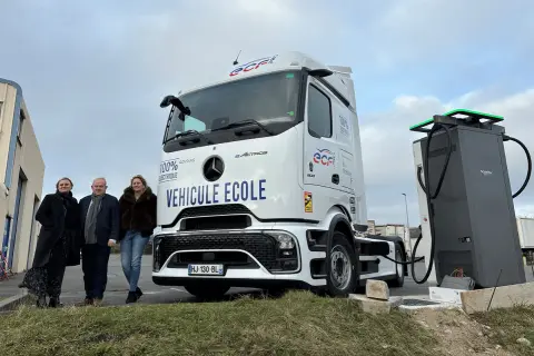 Trois personnes posent devant un camion école 100% électrique, prêt à être rechargé. L'avenir des camions électriques est en marche.