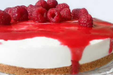 Cheesecake ai lamponi con coulis rosso e lamponi freschi, una delizia per gli occhi e per il palato.