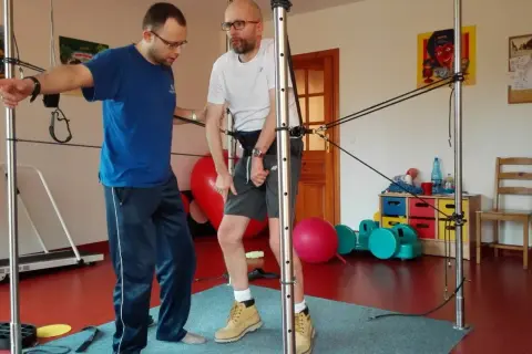 Fizjoterapeuta pomaga pacjentowi ćwiczyć z użyciem sprzętu do rehabilitacji po udarze mózgu.