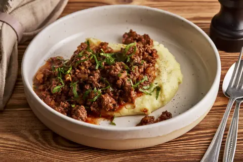 Herzhaftes Hackfleisch mit Tomatensauce auf cremigem Kartoffelpüree, garniert mit Petersilie. Ein einfaches und leckeres Haschee Rezept.