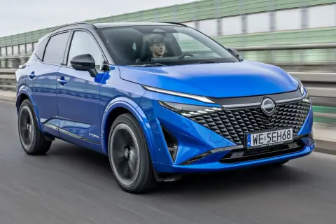 Niebieski Nissan Qashqai z kierowcą za kierownicą jedzie po drodze.