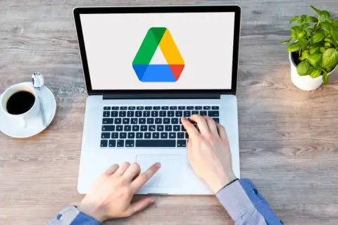 Frustrated hands try to access Google Drive on a laptop, but the screen shows only the logo, suggesting it's not loading.