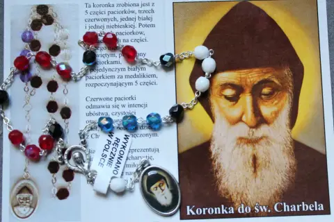 Koronka do św. Charbela, z kolorowymi paciorkami i medalikiem, obok wizerunku świętego. Idealna do odmawiania litanii do św. Charbela 9 dni.