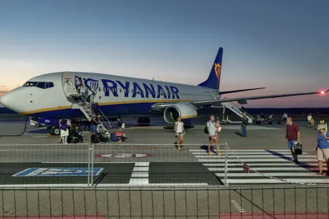 Ryanair przyloty Modlin: pasażerowie schodzą po schodkach z samolotu na płycie lotniska o zmierzchu.