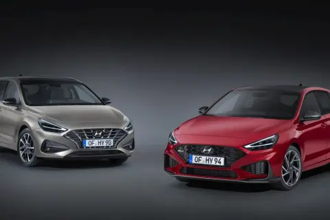 Dwa modele Hyundai i30 2024: jeden w kolorze złotym, drugi w czerwonym, prezentują nowoczesny design i sportowe linie.
