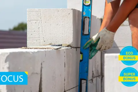 Costruzione con blocchi di calcestruzzo aerato autoclavato, livella in mano per un lavoro preciso. Eco e Super Bonus in evidenza.