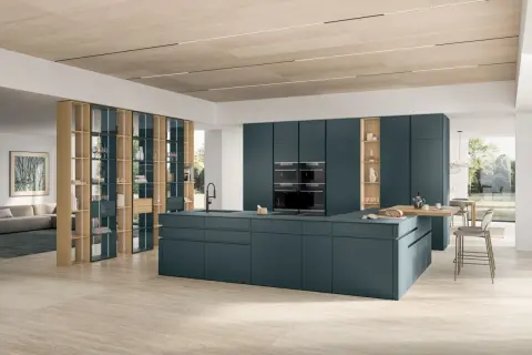 Un sol de cuisine tendance en travertin clair, réchauffant cet espace moderne aux meubles bleu pétrole.