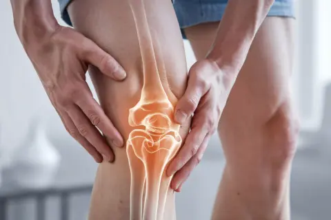 Hände umfassen ein Knie, das einen leuchtenden, anatomischen Knorpelaufbau des Knies zeigt, der auf Schmerz oder Verletzung hindeutet.