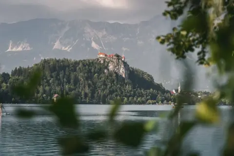 Jezioro Bled ze skalnym zamkiem, jedno z najpiękniejszych miejsc w Słowenii. Na pierwszym planie widać osobę na desce SUP.