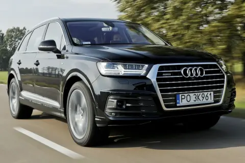 Czarny Audi Q7 2025 pędzi po drodze, otoczony zielenią drzew.