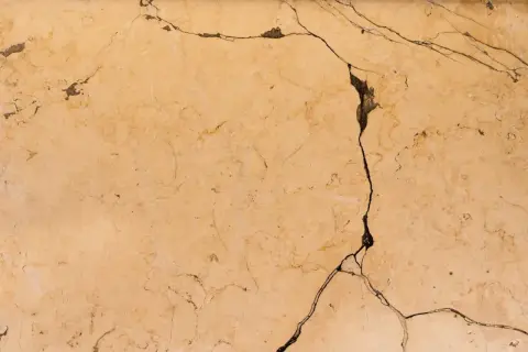 Surface de céramique beige fissurée, montrant comment réparer une céramique cassée.