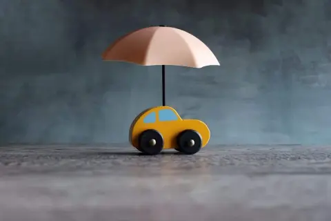Voiture jaune sous parapluie, symbolisant une assurance courte durée.