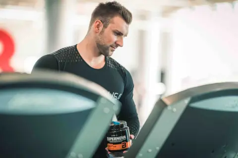 Mężczyzna z odżywką Supernova na bieżni, zastanawia się, czy robić cardio na masie.
