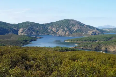 Paisaje sereno con un embalse azul rodeado de montañas verdes. La senda del Genaro se adentra en este idílico entorno natural.